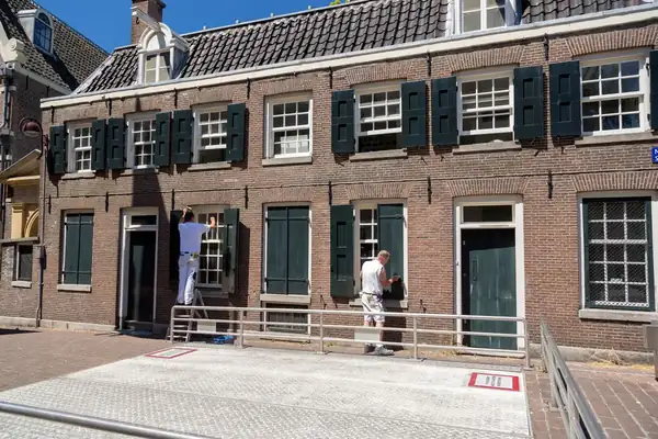 Twee schilders aan de gevel van een bakstenen huis